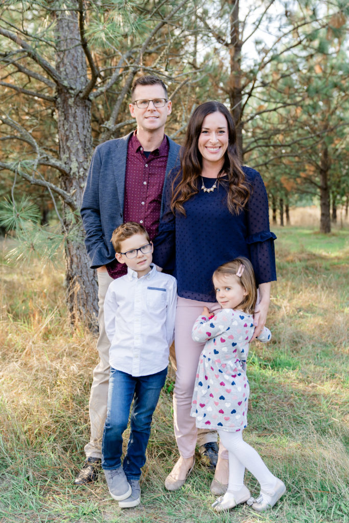 a beautiful oregon family session with ponderosa pine tress and the sun shining through featuring a father, mother, son and daughter