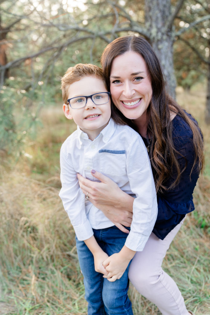 a beautiful oregon family session with ponderosa pine tress and the sun shining through featuring a mother and son smiling at the camera