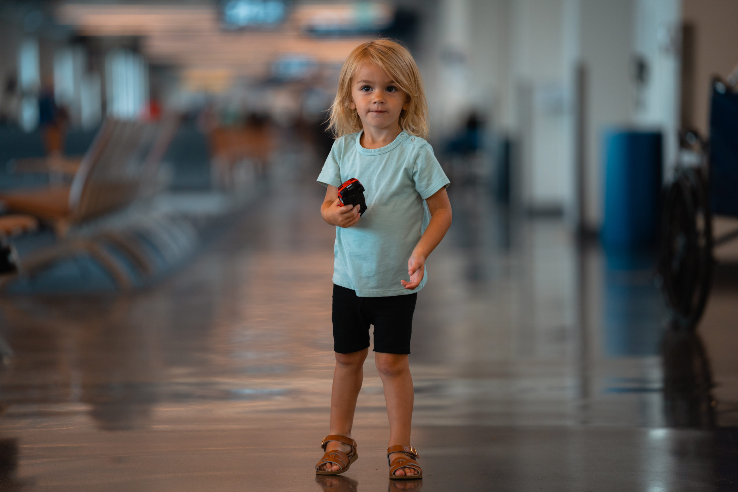 child holding car in airport terminal